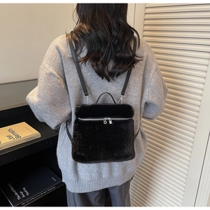 Detail eines schwarzen Plüschrucksacks mit silbernen Reißverschlüssen am Model