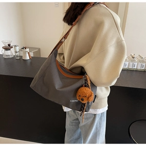Detail of grey canvas tote bag with brown leather trim and a cute plush dog charm