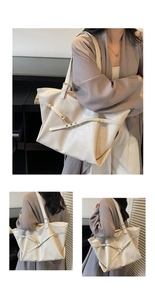 Detail of creamy white tote bag featuring lychee texture leather and gold metal buckles