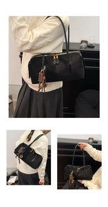 Détail du sac à bandoulière en daim noir avec double zip doré et pendentif chocolat
