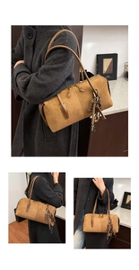 Détail du sac Boston en daim caramel avec poignées en cuir et breloque chocolat décorative