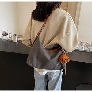 Detailed shot of canvas shoulder bag with leather trim and cute puppy plush pendant