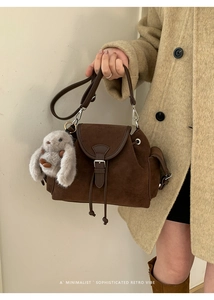 Close-up of retro brown faux suede bucket bag with plush rabbit charm detail