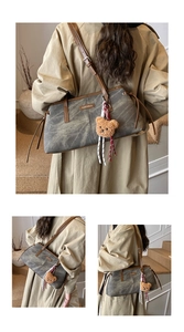 Detail of vintage gray shoulder bag with brown straps and cute plush bear charm