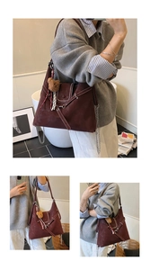 Detail view of large burgundy tote bag with contrast stitching and bear charm