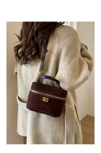 Détail du sac à main en daim marron foncé avec fermoir doré sur un manteau beige