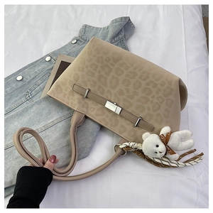 Detail of leopard print tote bag with plush bear charm and woven tassel accent