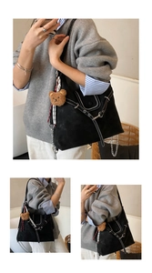 Detail of black suede tote bag with white contrast stitching and metallic rivets