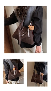 Detail of dark brown suede tote bag with chain strap, studs, and teddy bear charm