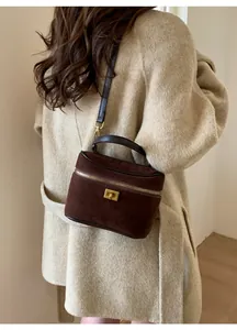 Vue détaillée du sac boîte en daim marron foncé avec fermoir doré sur manteau