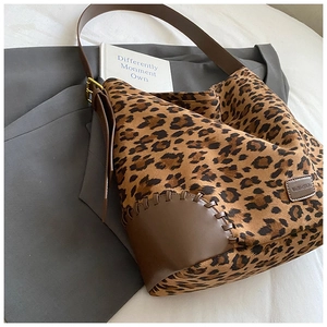 Detail of leopard print tote bag with brown leather corners and adjustable gold buckle