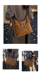 Detail of brown vintage tote with white stitching, metal chain and plush ball charm