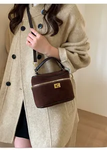 Détail du sac boîte en daim marron foncé avec ferrures dorées et fermoir tournant
