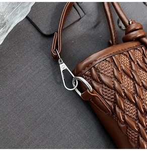 Detailed view of chocolate brown woven bucket bag strap with silver metal lobster clasp