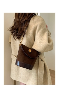 Close-up of vintage brown suede bucket bag with leather trim and gold fashion emblem