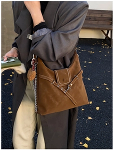 Detail of dark brown suede shoulder bag with contrast stitching and silver metal chain