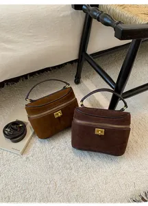Gros plan de sacs à main en daim caramel et marron avec fermetures éclair et verrous métal