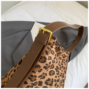 Close-up of leopard print crossbody bag with leather strap and gold buckle detail