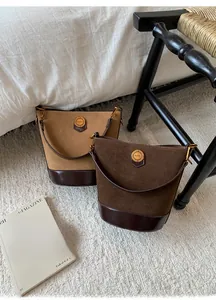 Detail of vintage bucket bags in light and dark brown suede with golden metal hardware