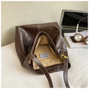 Détails de l'intérieur du sac seau marron foncé montrant la doublure et la poche zippée