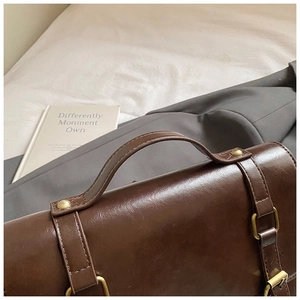 Dettaglio della borsa a tracolla vintage marrone con fibbia retrò e cuciture curate