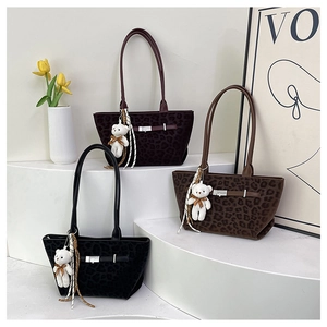Detailed view of leopard print tote bags in black, brown, and purple with plush bear charm