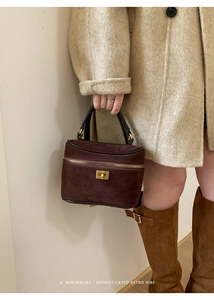 Détail d'un mini sac à main en daim marron foncé avec fermeture éclair dorée et fermoir