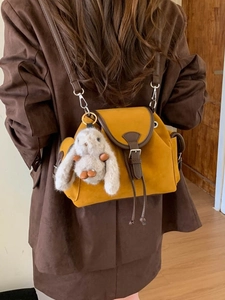 Yellow crossbody bucket bag with brown strap and plush rabbit charm on model
