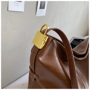 Détail du sac seau vintage en cuir marron avec cadenas doré et coutures de précision