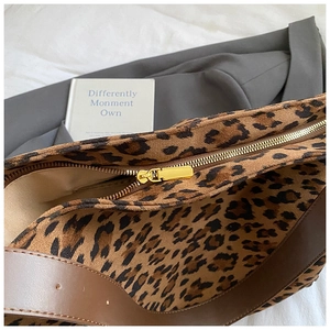 Detailed close-up of leopard print canvas shoulder bag with premium gold metal zipper