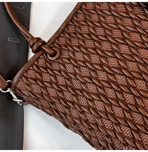 Close-up of deep brown woven texture on bucket bag with metal hook and knot detail