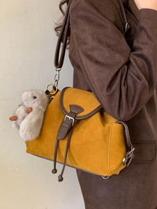 Fashionable mustard yellow suede crossbody bucket bag with brown trim and plush bunny