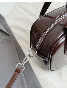 Detailed close-up of glossy dark brown leather bowling bag with silver zipper and hardware