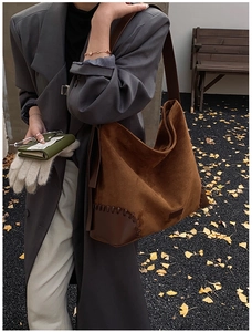 Detailed view of caramel suede hobo bag featuring dark leather corner patches and stitching