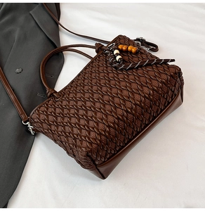 Detail of dark brown woven bucket bag with wood bead tassel and detachable strap