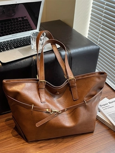 Vintage brown leather tote bag with large capacity and double handles on a wooden table
