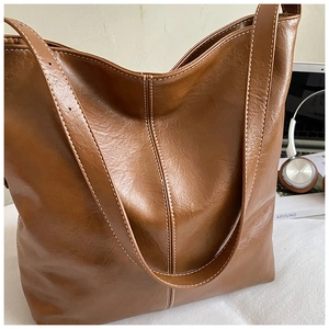 Détail du grand sac cabas marron avec coutures blanches dans un décor de bureau moderne