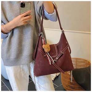 Detail of dark burgundy tote bag with white contrast stitching and cute bear charm