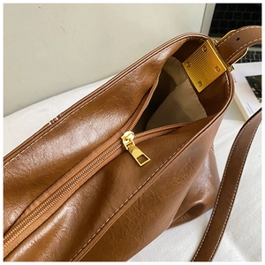 Détail du sac seau marron montrant les surpiqûres blanches et la fermeture éclair dorée