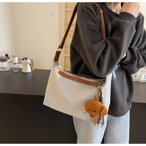 Close-up of canvas tote bag with brown leather straps and cute plush bear charm