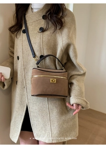 Mini sac boîte en daim marron avec poignée en cuir noir porté par un mannequin chic