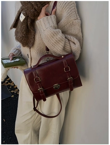 Dettaglio borsa vintage bordeaux con doppie fibbie e chiusura a scatto in metallo dorato