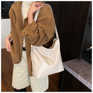 Détail du grand sac seau blanc crème porté avec une veste en daim marron élégante