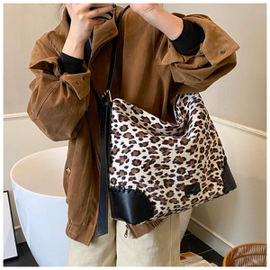 Detail view of leopard print shoulder bag with black leather base and wide strap
