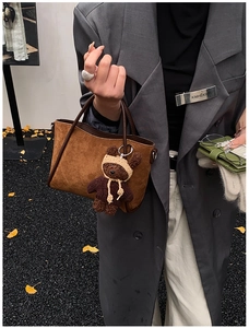 Detail der Vintage-Eimer-Tasche aus Wildleder mit süßem Teddybär-Plüsch-Anhänger