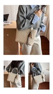 Detail of beige woven tote bag with beaded tassel and adjustable shoulder strap