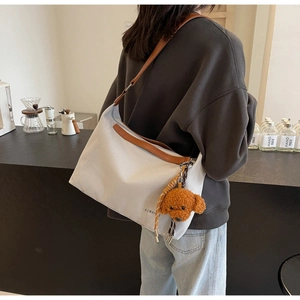 Grey canvas tote bag with brown leather straps and a cute plush dog charm detail
