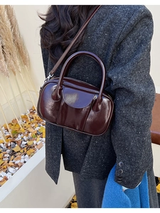 Detail of dark brown glossy leather bowling bag with vintage texture and silver hardware