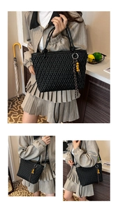 Detail of black quilted bucket bag with yellow bead charm in a lifestyle home setting