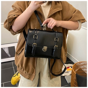 Dettaglio di una borsa a tracolla nera vintage con fibbie in un contesto casual